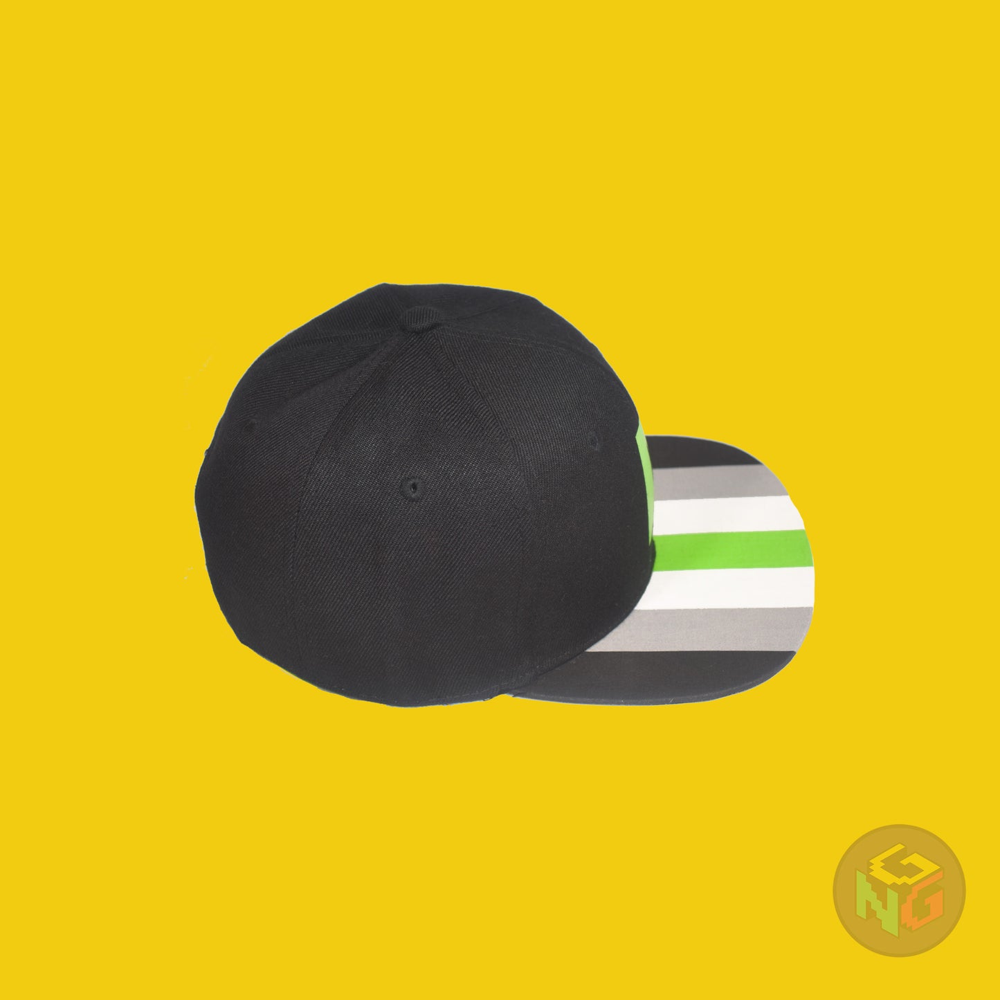 Black flat bill snapback hat. The brim has the agender pride flag on both sides and the front of the hat has a green letter “A”. Top right view