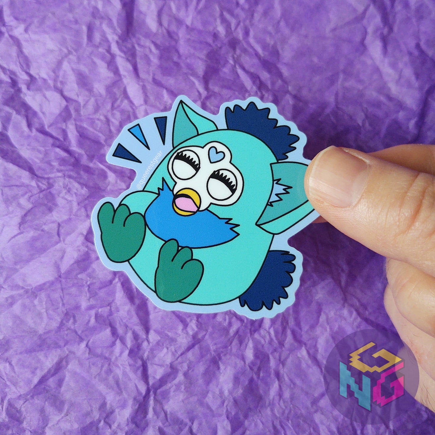 gay laughing furby sticker held in front of purple background