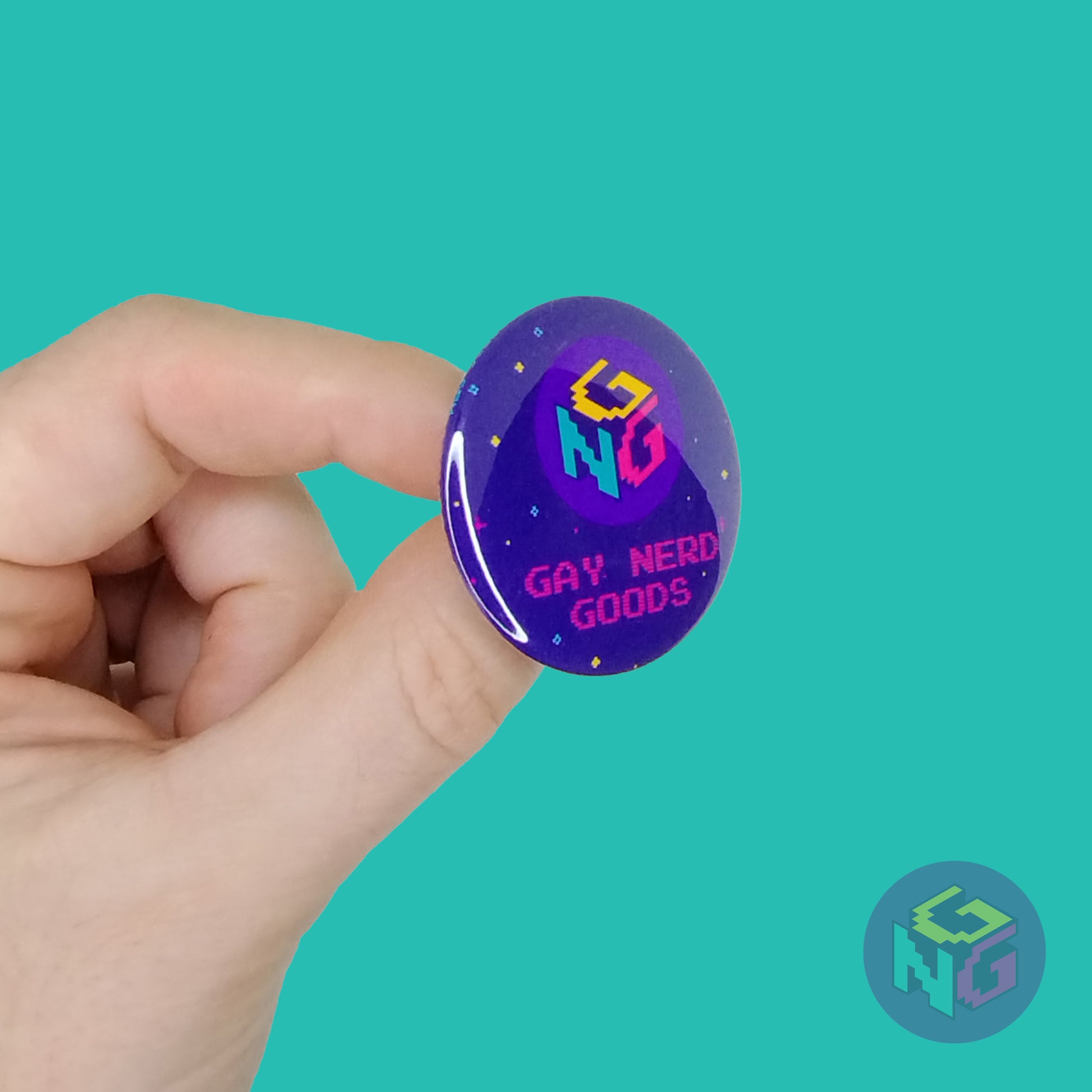 light skinned hand holding 1.5" round pinback button angled to the right with gay nerd goods logo against mint background