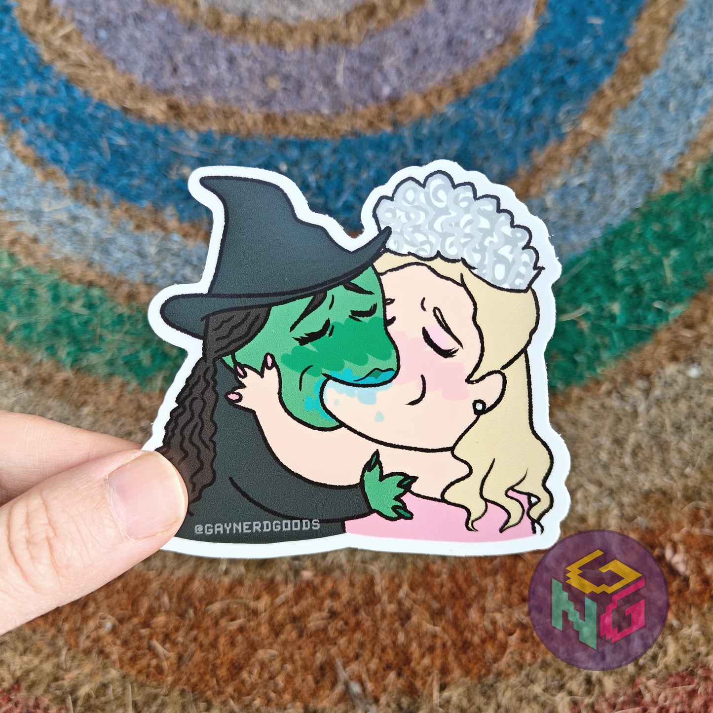 glinda and elphaba kissing waterproof sticker held in front of neutral and rainbow background