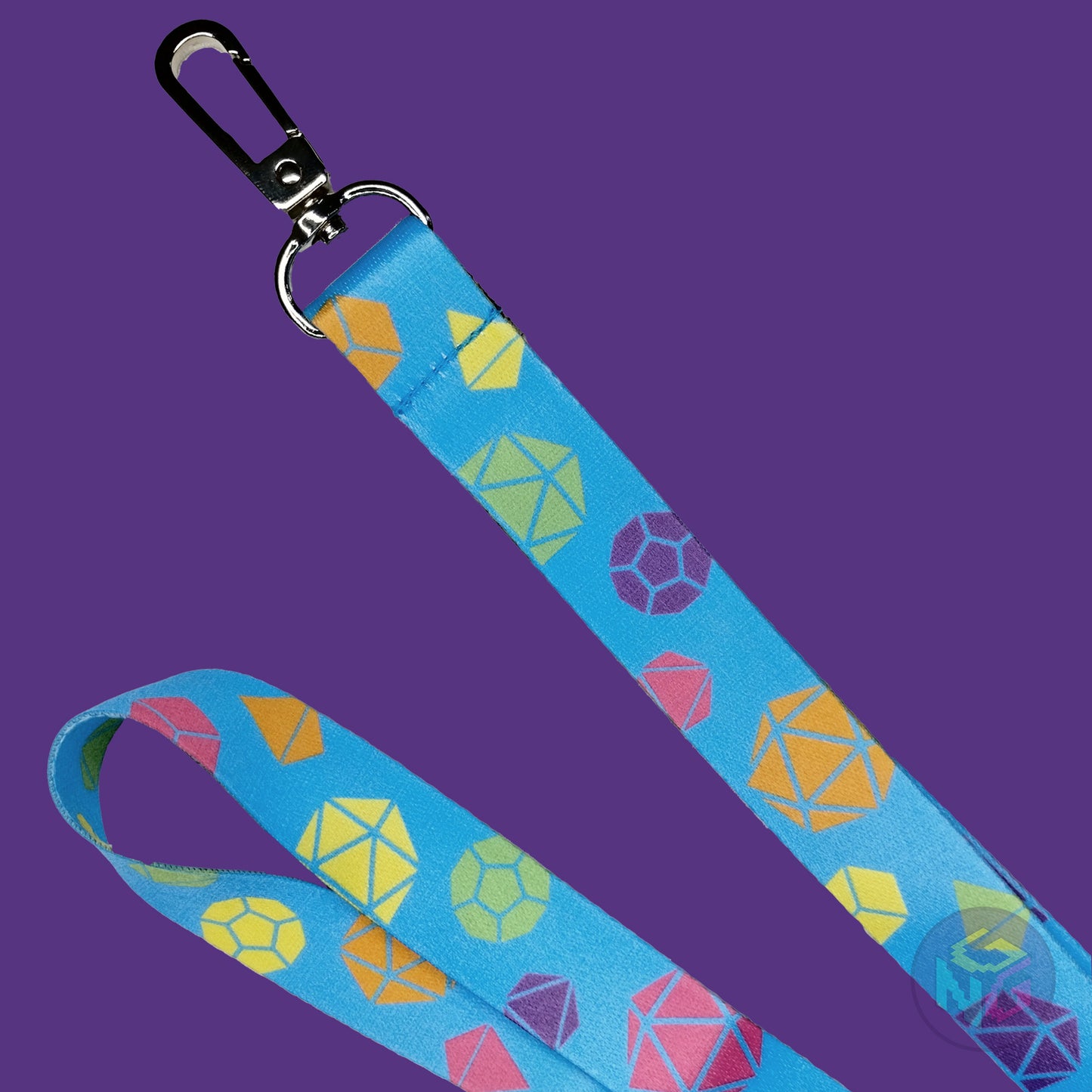 close up detail of the rainbow dungeons and dragons lanyard showing the lobster clasp, green d20s, orange d6s, yellow d4s, purple d12s, pink d8s, and other dice