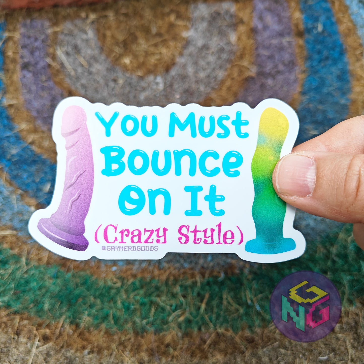 Waterproof sticker with text 'You Must Bounce On It (Crazy Style)' held by a hand on a textured surface.