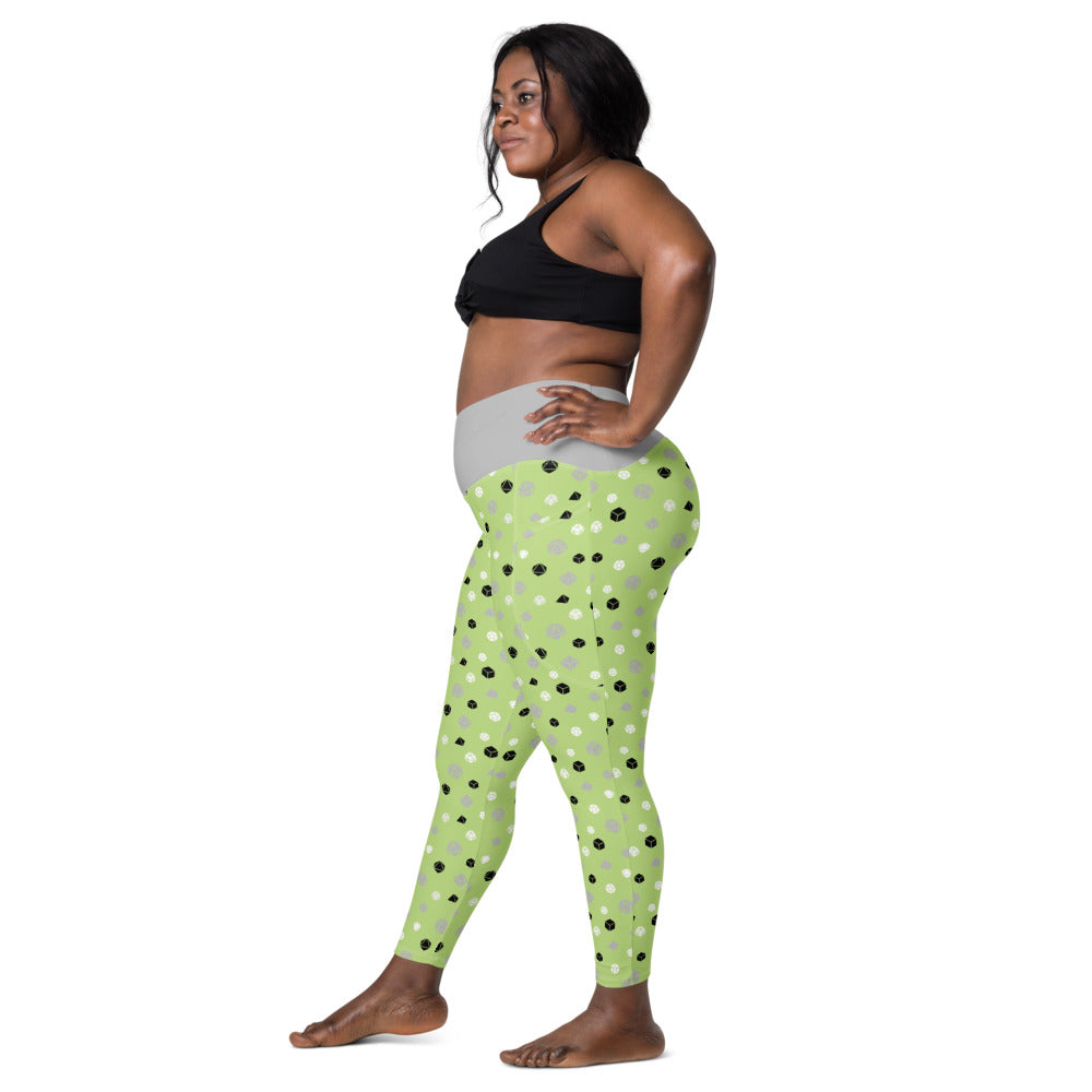 Left side view of dark-skinned female-presenting model wearing the agender dice leggings and black sports bra. She is facing left with her left hand on her hip and right leg forward
