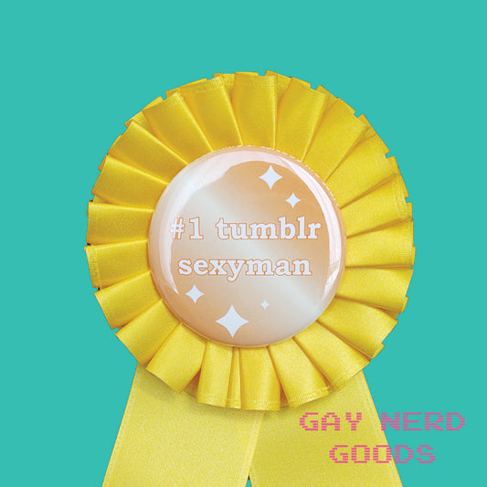 close up  view of the award ribbon. The central button says "#1 tumblr sexyman" surrounded by white sparkles on a gold gradient background. it's surrounded by yellow satin ribbon