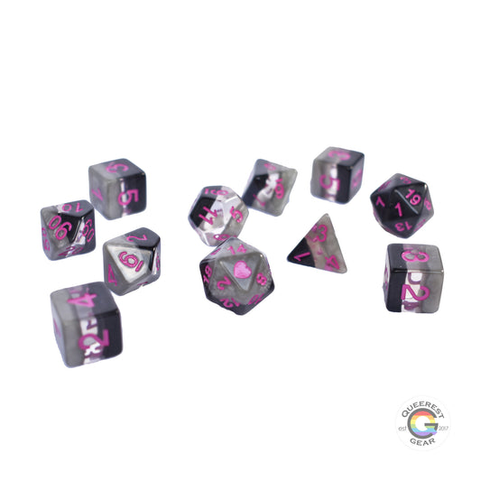 11 piece set of polyhedral dice scattered on a white background. They are transparent and colored in the stripes of the demisexual flag with magenta ink