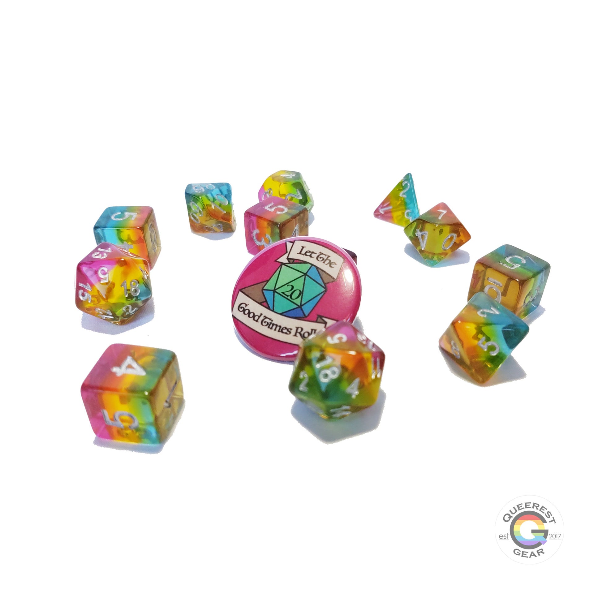 11 piece set of pansexual dice scattered on a white background. They are transparent and colored in the stripes of the nonbinary flag with silver ink. There is the freebie “let the good times roll” pinback button among them. 