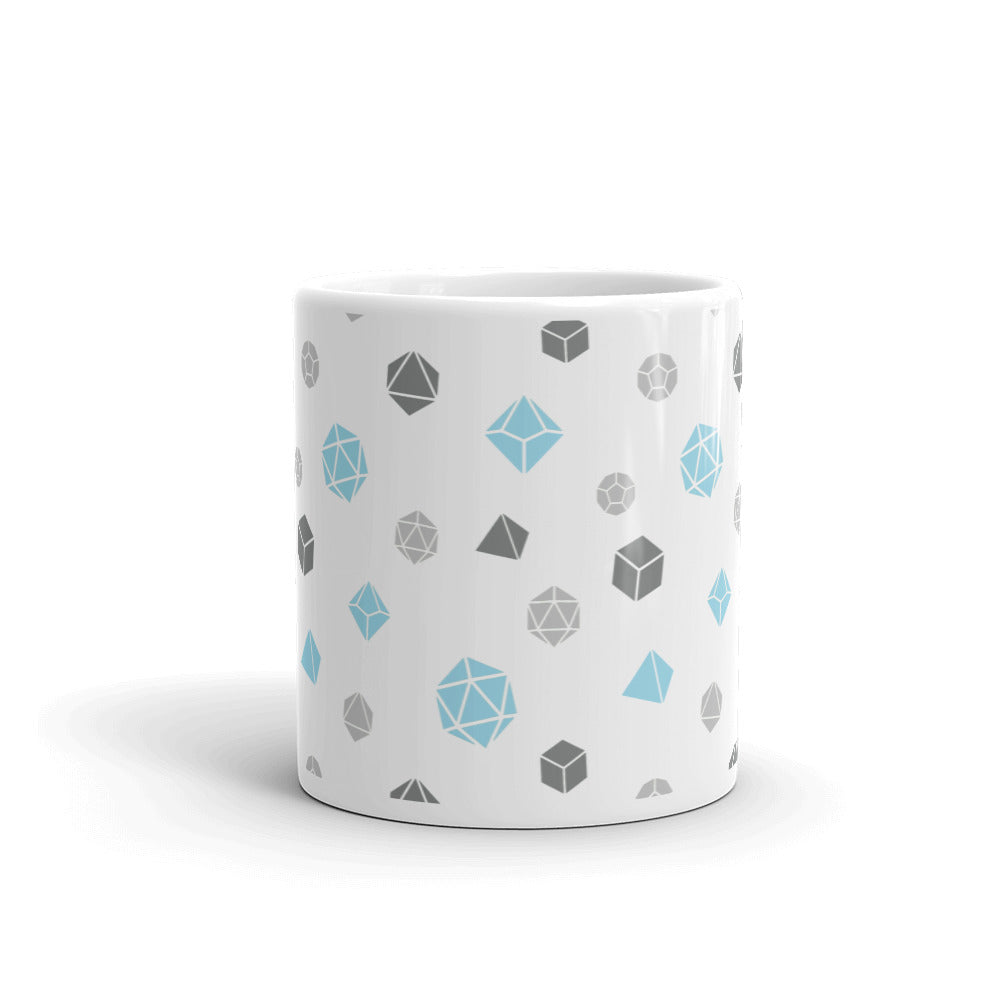 white mug on a white background with handle facing back. It has an all-over print of polyhedral d&d dice in the demiboy colors of dark grey, light grey, blue