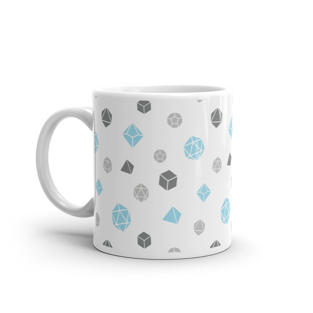 white mug on a white background with handle facing left. It has an all-over print of polyhedral d&d dice in the demiboy colors of dark grey, light grey, and blue