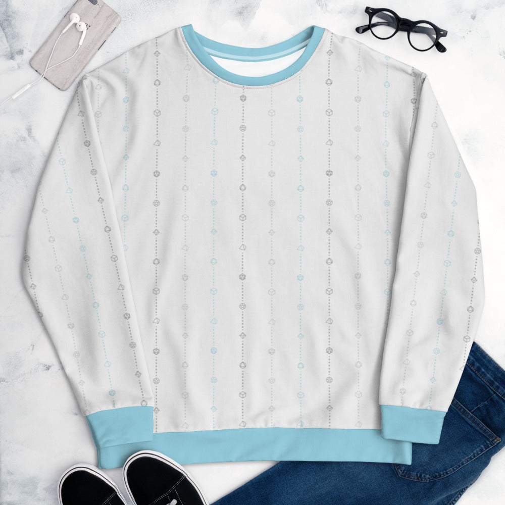The demiboy pride sweater laying flat, surrounded by clothes, a phone, and glasses. the sweater is white and has stripes of dashed lines and polyhedral dnd dice in greys and blue. The cuffs, collar, and waistband are a matching blue
