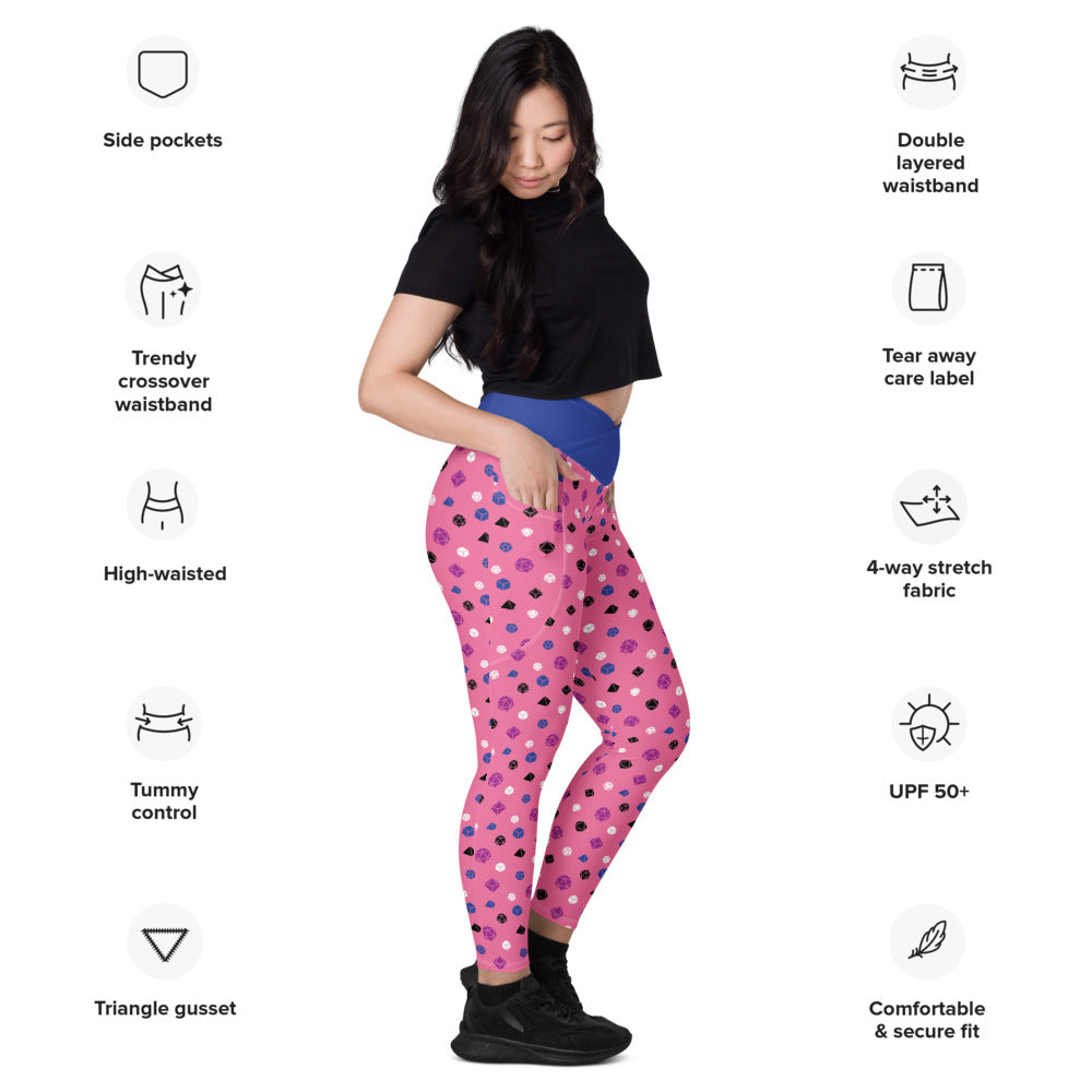 Light-skinned dark-haired female-presenting model wearing the genderfluid dice leggings. she is facing right and has a hand in the pocket. she is surrounded by product specs: "side pockets, trendy crossover waistband, high-waisted, tummy control, triangle gusset, double layered waistband, tear away care label, 4-way stretch fabric, UPF 50+, comfortable & secure fit"