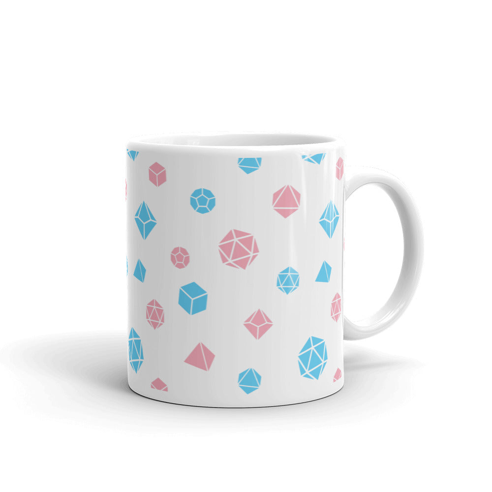 white mug on a white background with handle facing right. It has an all-over print of polyhedral d&d dice in the transgender colors of pink and blue