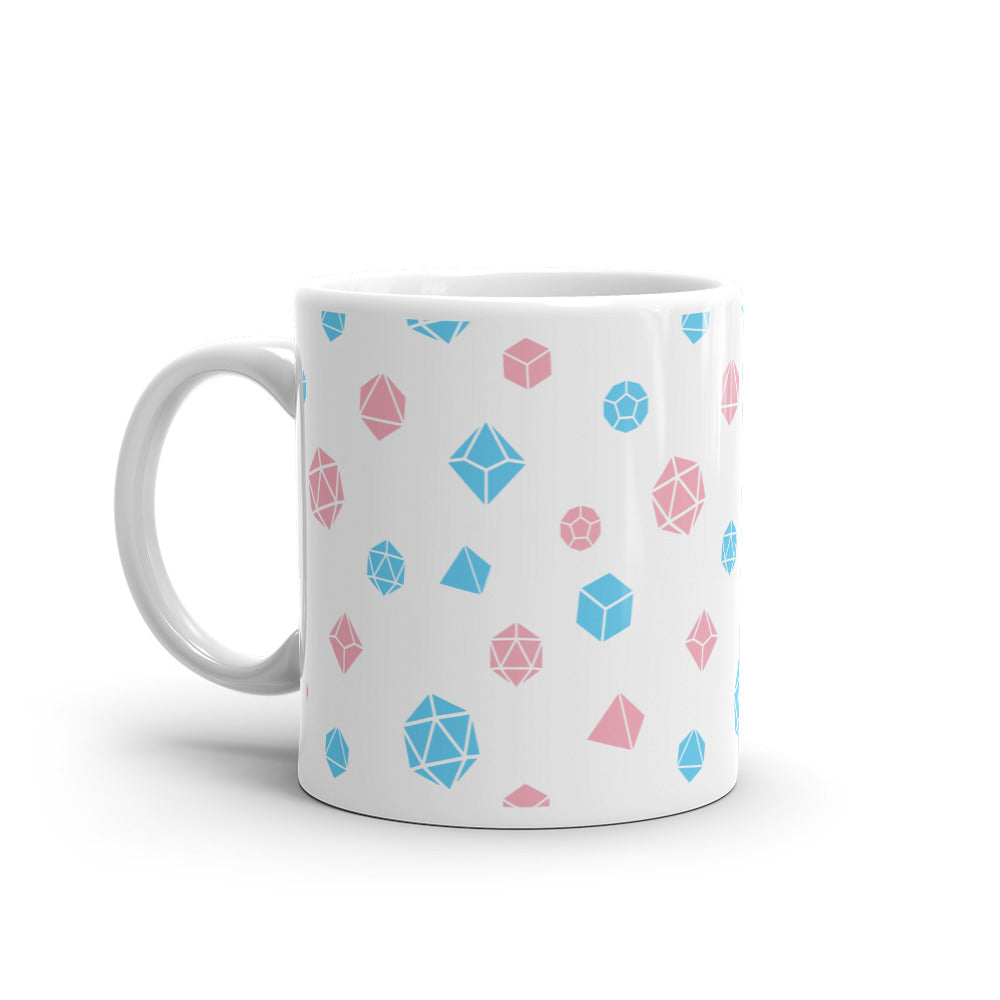white mug on a white background with handle facing left. It has an all-over print of polyhedral d&d dice in the transgender colors of pink and blue