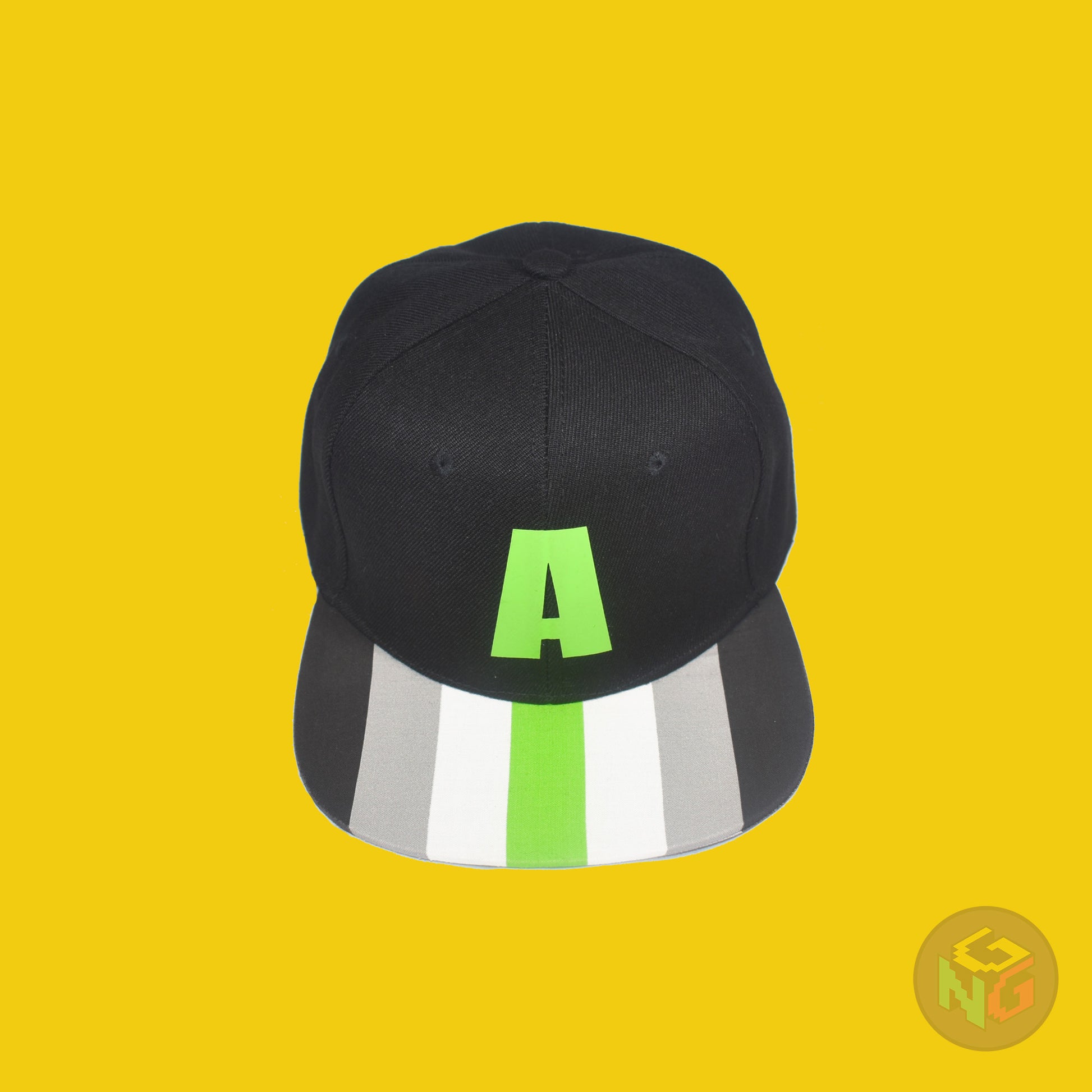 Black flat bill snapback hat. The brim has the agender pride flag on both sides and the front of the hat has a green letter “A”. Top view