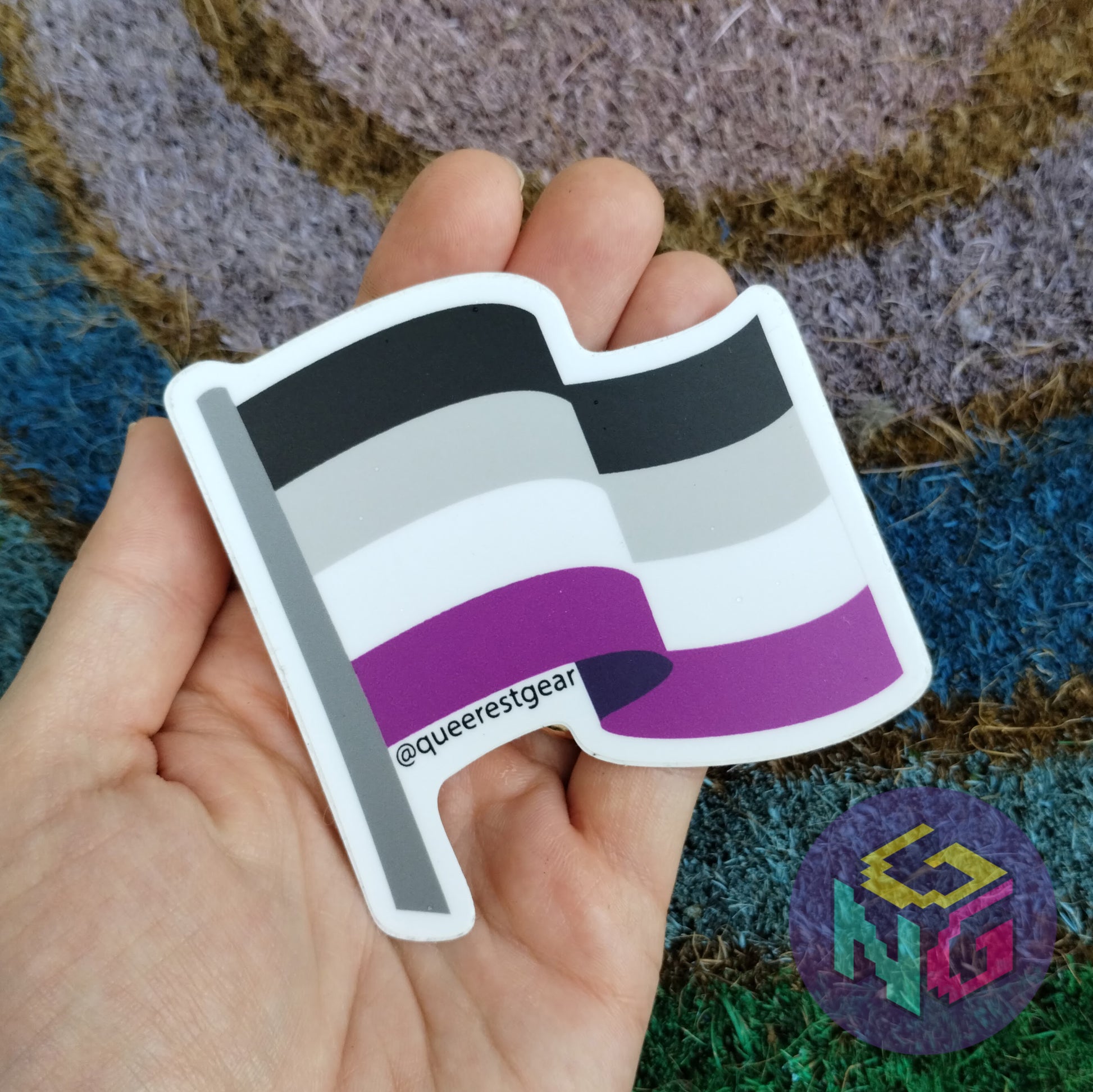 asexual flag sticker held in hand on a rainbow welcome mat