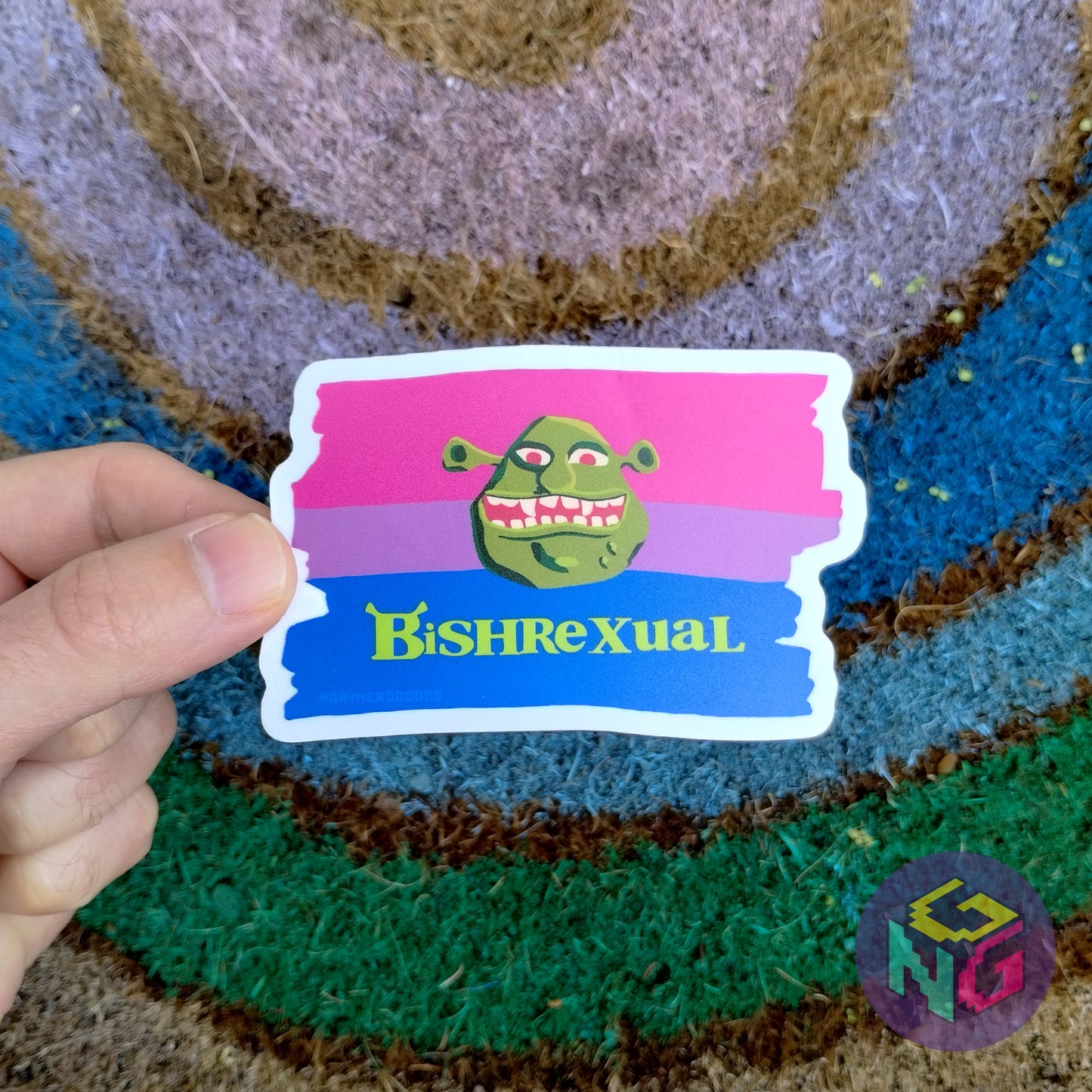 vinyl bisexual bishrexual sticker held in a hand in front of a rainbow welcome mat