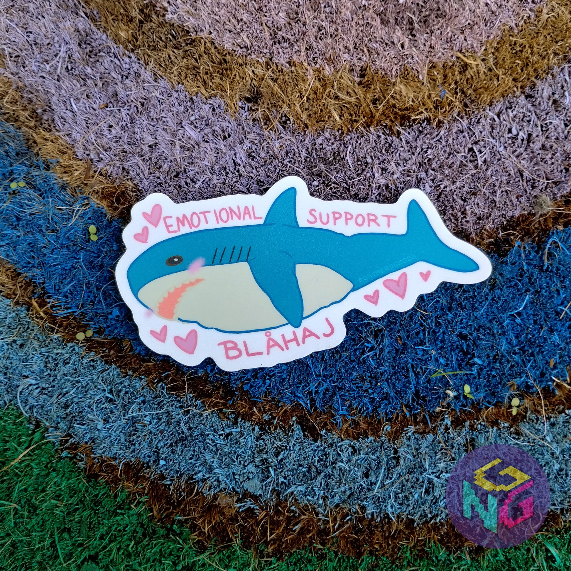 emotional support blahaj sticker lying flat on rainbow welcome mat