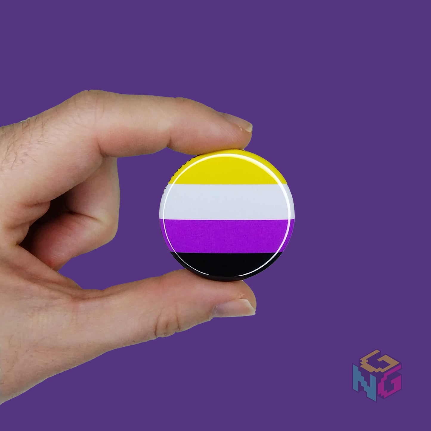 nonbinary pride pin held in a hand held in front of a purple background