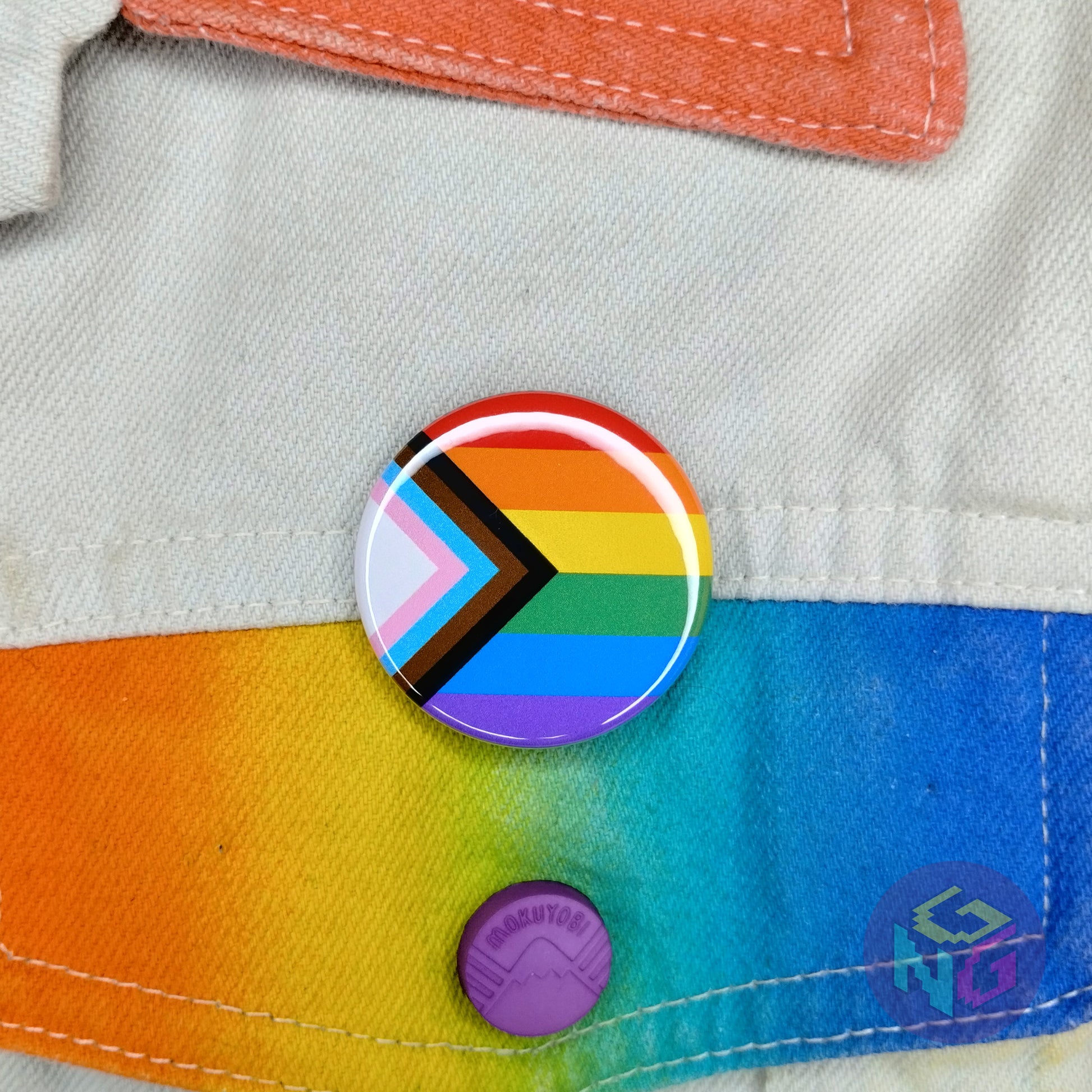 progress pride inclusive round flag button pinned to white denim jacket with rainbow details