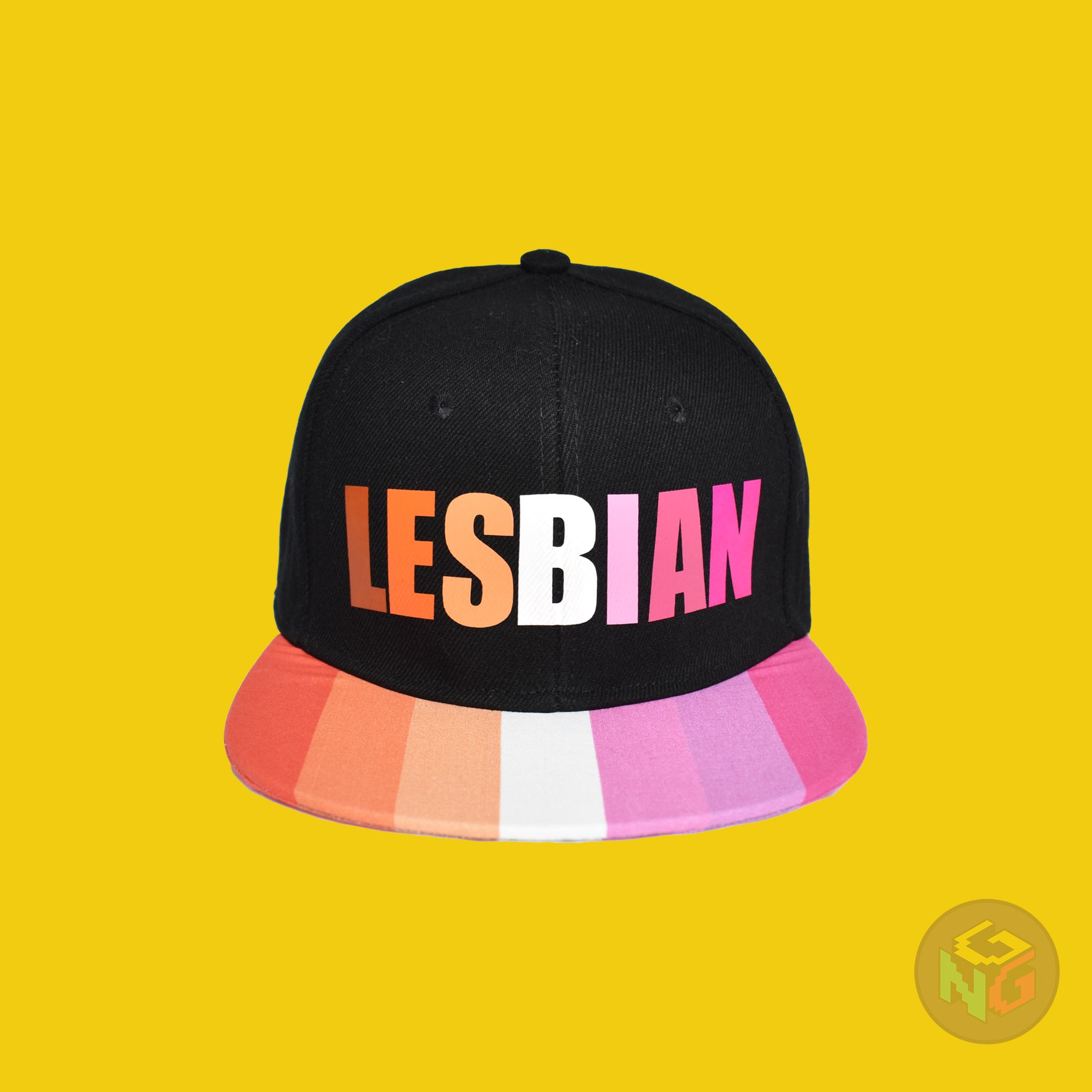 Black flat bill snapback hat. The brim has the lesbian pride flag on both sides and the front of the hat has the word “LESBIAN” in orange, pink, and white letters. Front view