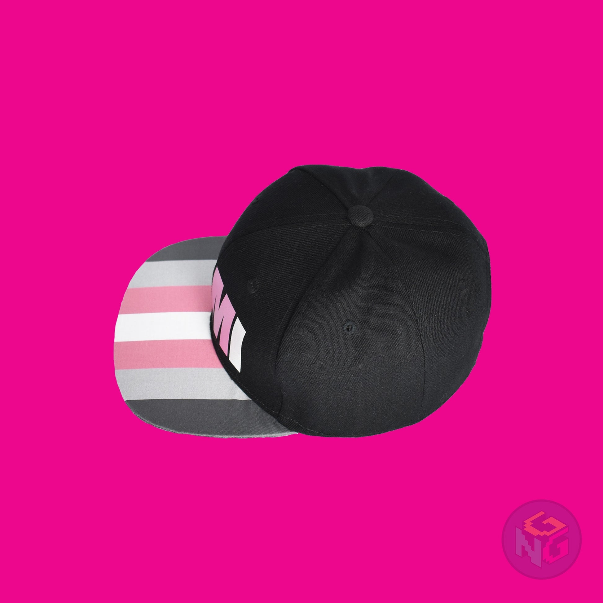 Black flat bill snapback hat. The brim has the demigirl pride flag on both sides and the front of the hat has the word “DEMI” in dark grey, light grey, pink, and white. Top left view