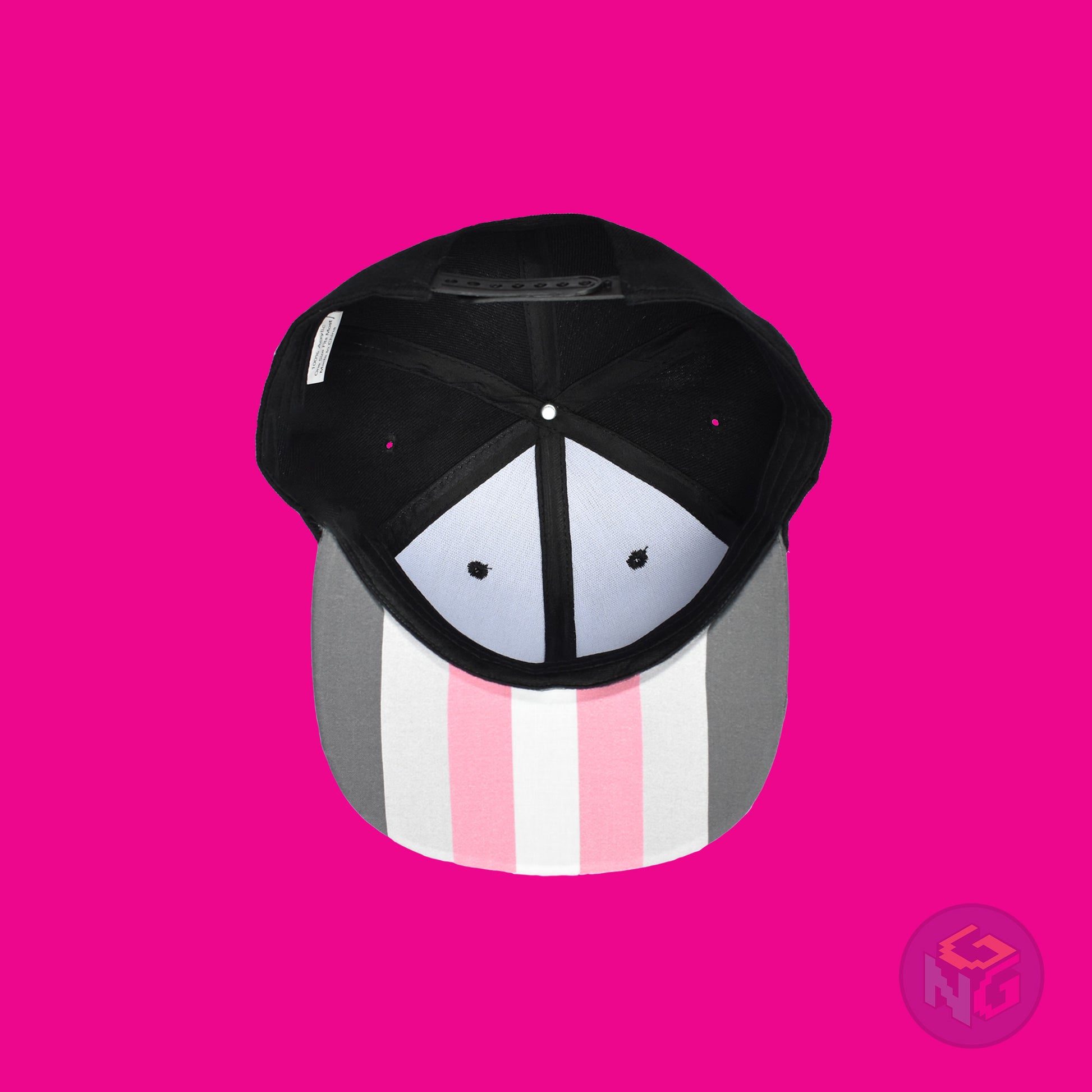 Black flat bill snapback hat. The brim has the demigirl pride flag on both sides and the front of the hat has the word “DEMI” in dark grey, light grey, pink, and white. Underside view