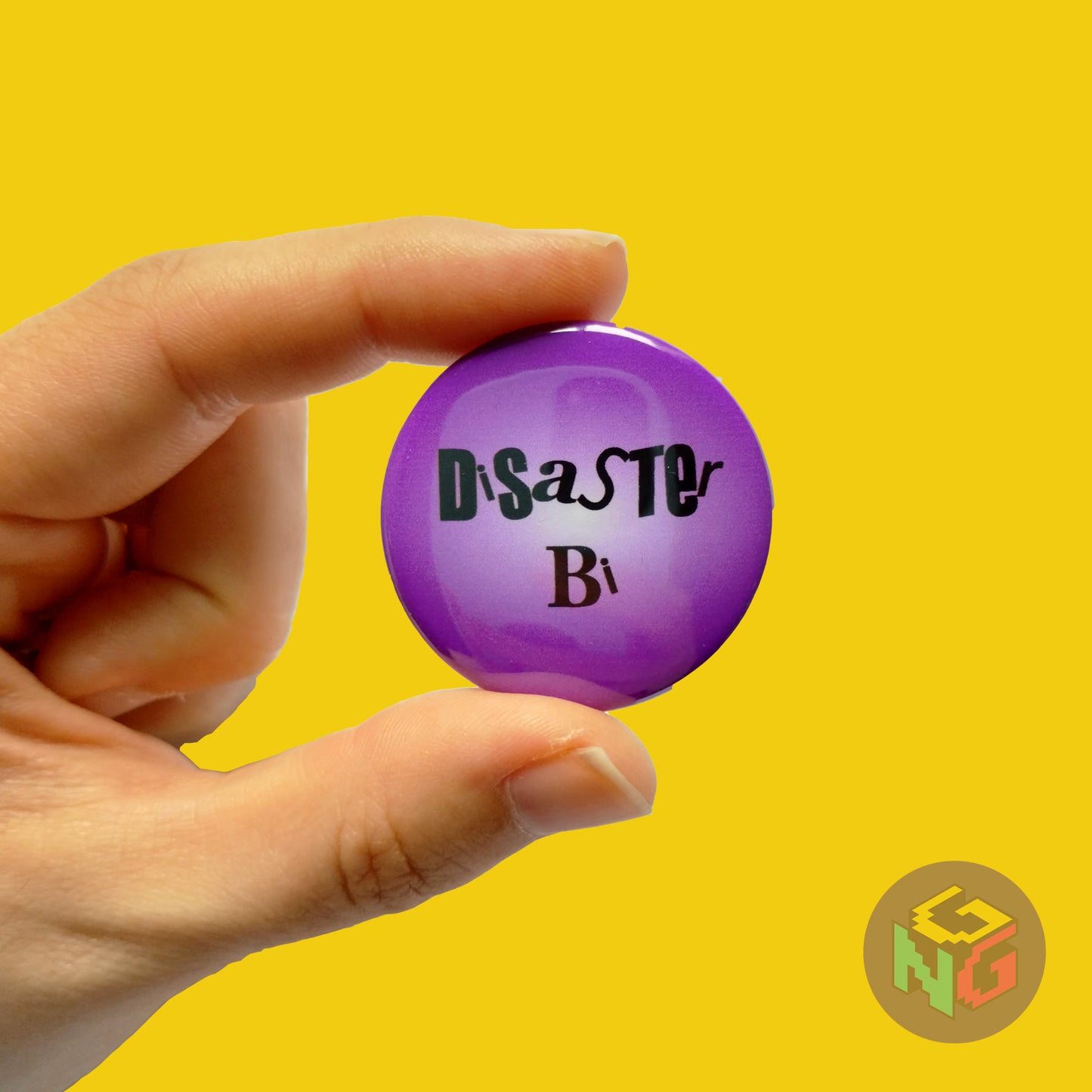 purple disaster bi button held in hand in front of yellow background