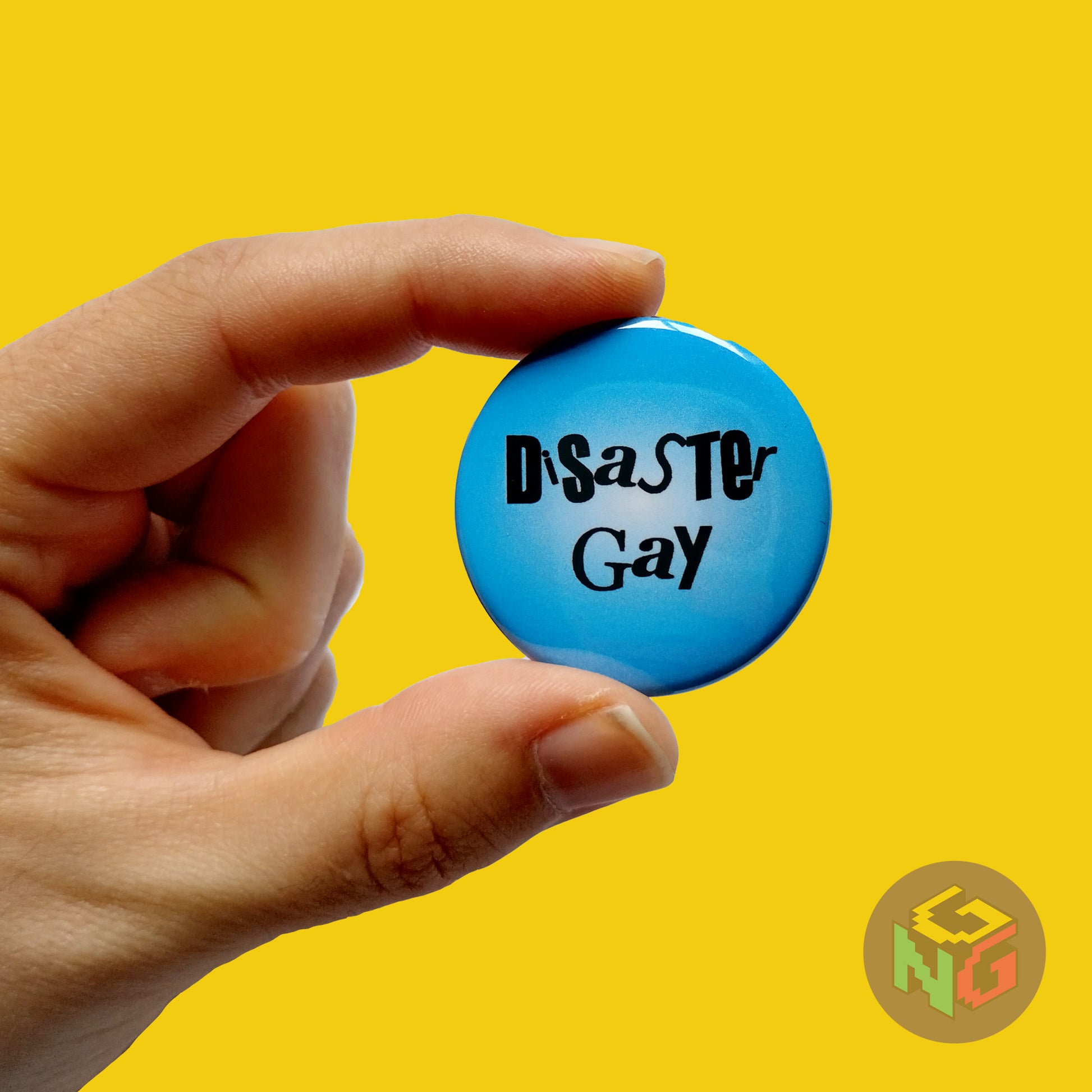 disaster gay button held in hand in front of yellow background