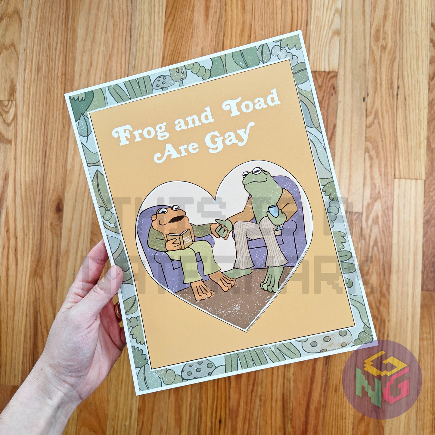 art print of imagined frog and toad book cover showing frog and toad holding hands and the title "frog and toad are gay" in front of wood background