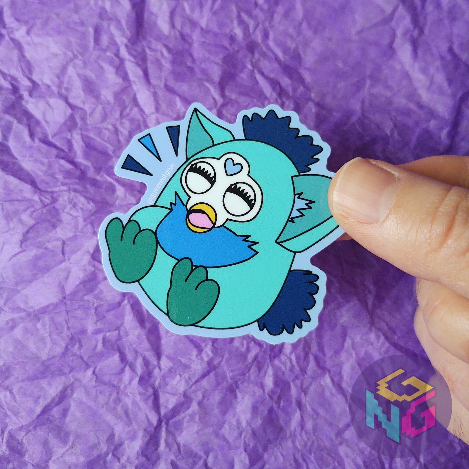 gay laughing furby sticker held in front of purple background