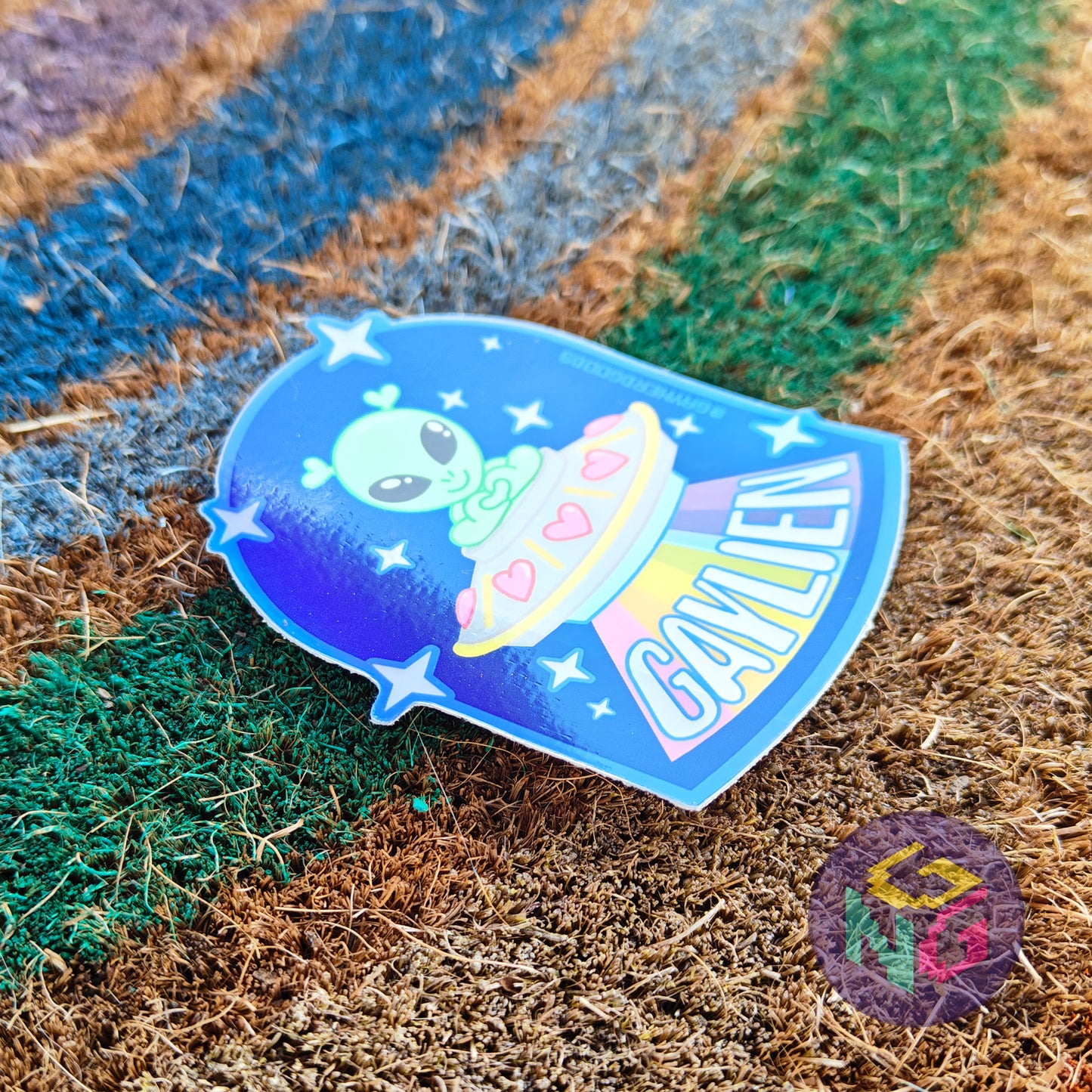 gaylien holographic alien sticker with a littel green alien in a spaceship with a rainbow beam laying at an angle