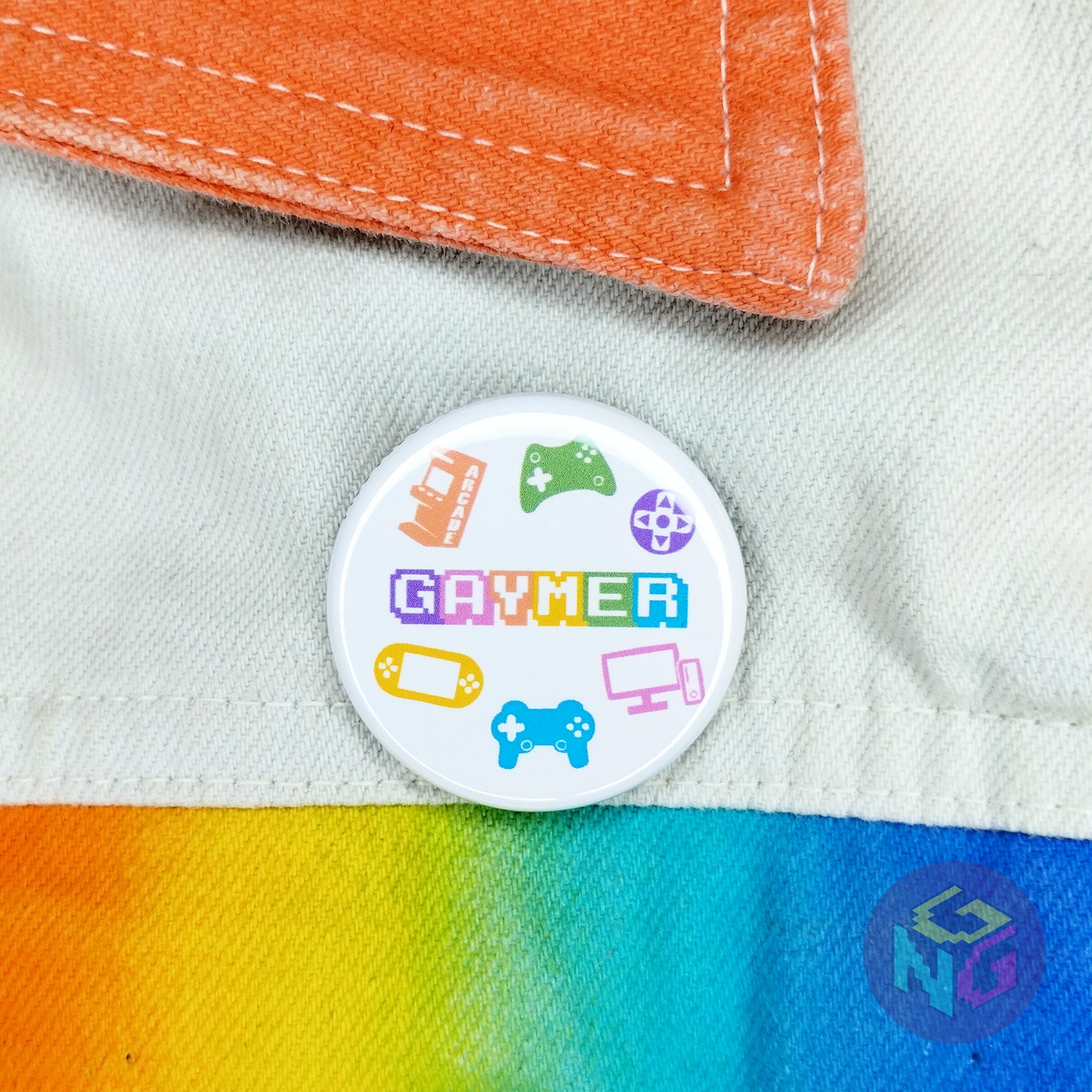 round white gaymer pin on background of white denim jacket with rainbow accents