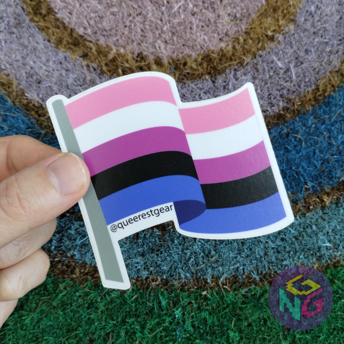 genderfluid flag sticker held in front of rainbow welcome mat