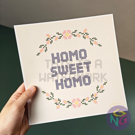 art print in an embroidery style showing a circle of flowers and the text "homo sweet homo"