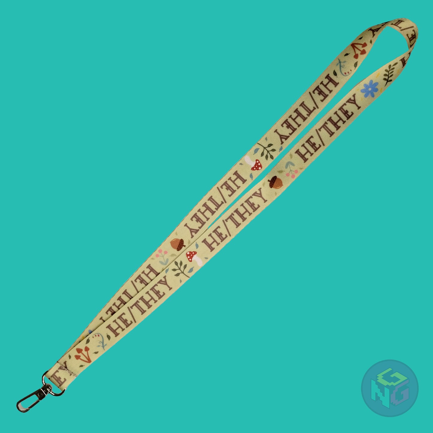 the green he they cottagecore lanyard lying flat showing the complete design and repeating pattern of acorns, berries, mushrooms, leaves, and he they pronouns