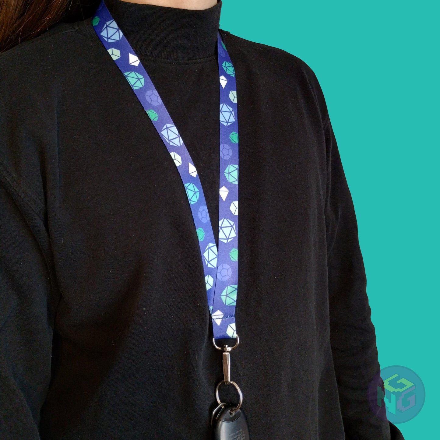 blue gay mlm pride lanyard being worn by a flat chested person wearing a black turtleneck. The end of the lanyard falls between their sternum and bellybutton and has a key fob clipped to the end