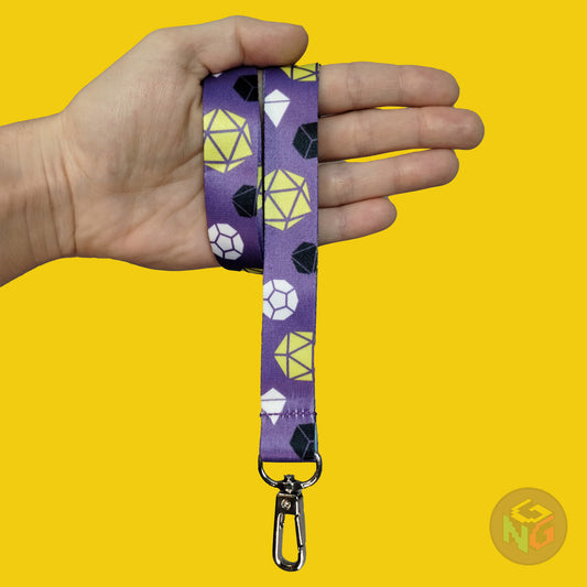 purple nonbinary dice lanyard wrapped around a hand with the lobster clasp dangling against a yellow background