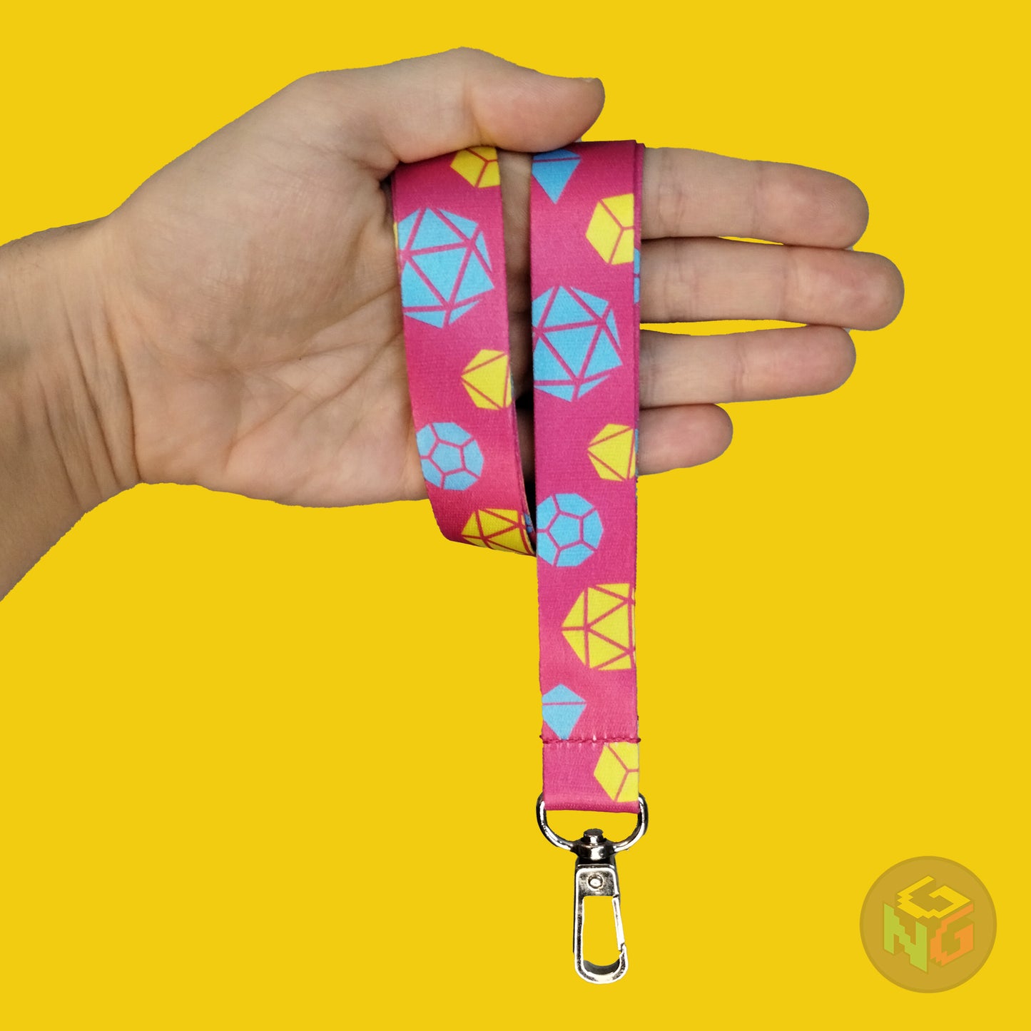 pink pansexual dice lanyard wrapped around a hand with the lobster clasp dangling against a yellow background