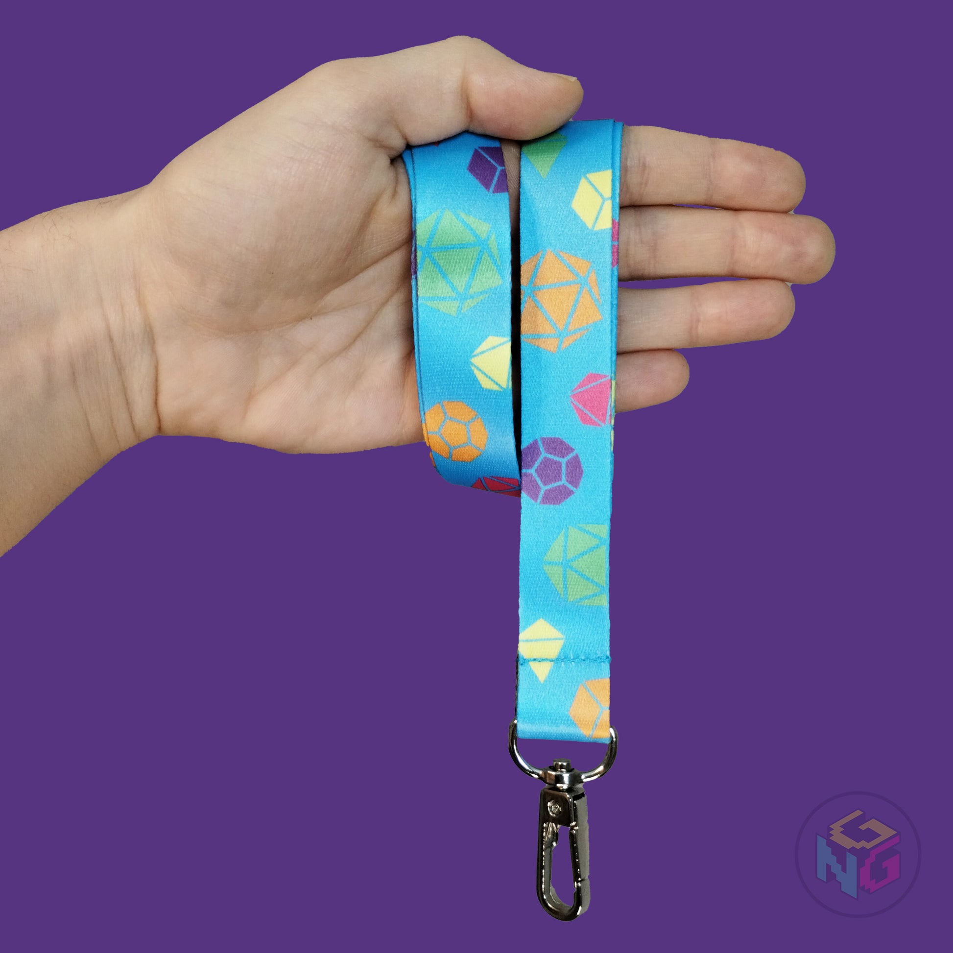 blue rainbow dice lanyard wrapped around a hand with the lobster clasp dangling against a purple background