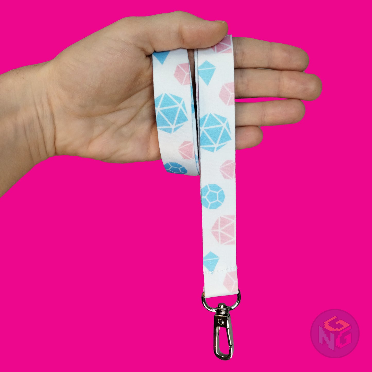 white transgender dice lanyard wrapped around a hand with the lobster clasp dangling against a pink background