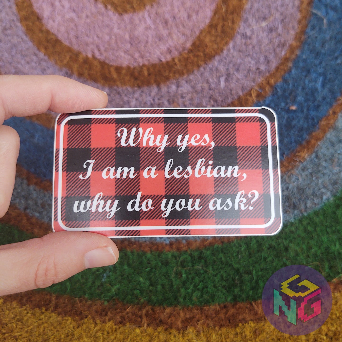 why yes i am a lesbian plaid flannel vinyl sticker held in front of rainbow welcome mat