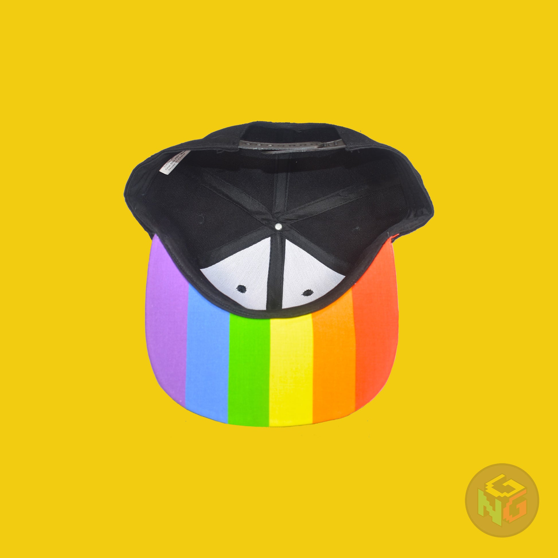 Black flat bill snapback hat. The brim has the rainbow pride flag on both sides and the front of the hat has the word “LESBIAN” in rainbow letters. Underside view