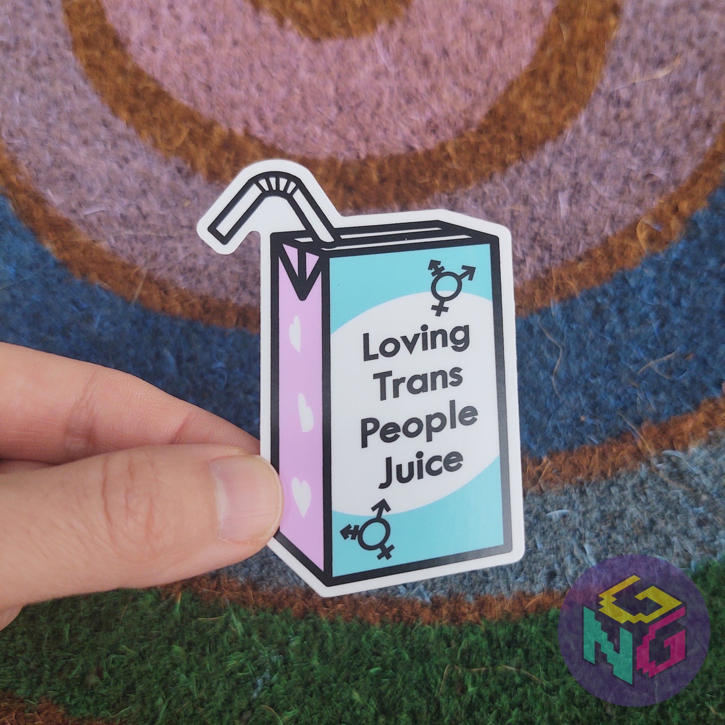 loving trans people juice sticker held in front of rainbow welcome mat