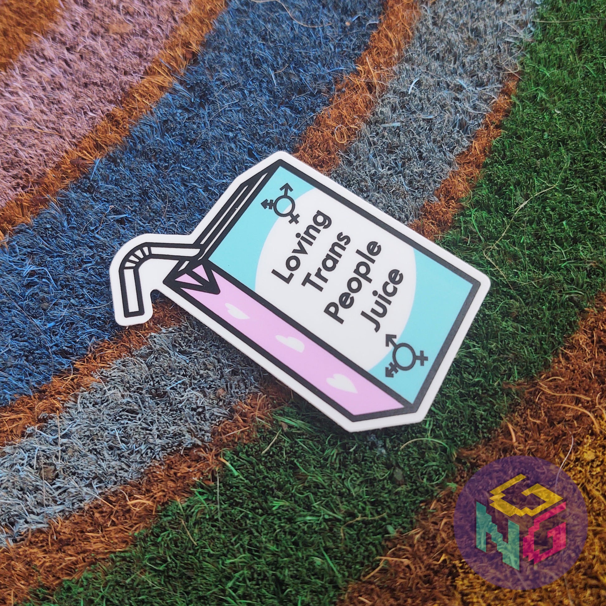 loving trans people juice sticker lying flat at an angle on top of a rainbow welcome mat