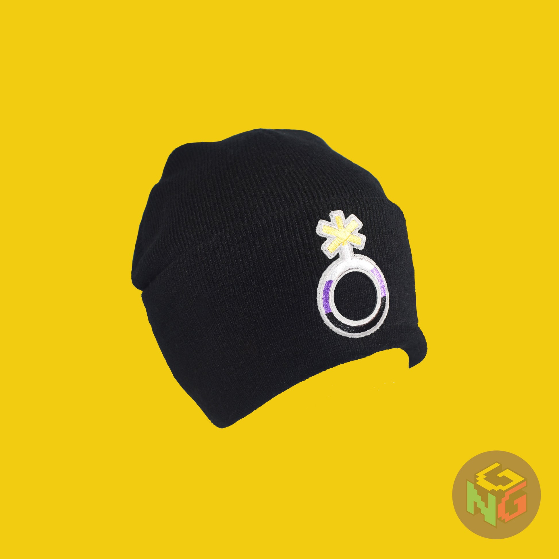 Black knit fabric beanie with the nonbinary symbol in yellow, white, purple, and black on the front. It is stretched and viewed in 3/4 on a yellow background
