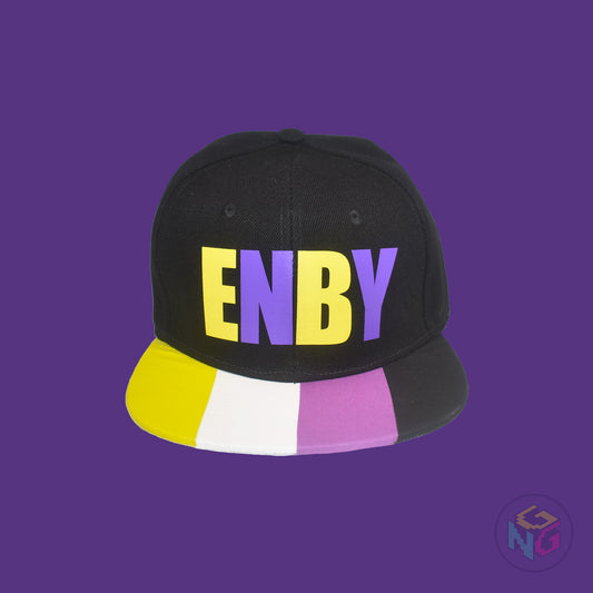 Black flat bill snapback hat. The brim has the nonbinary pride flag on both sides and the front of the hat has the word “ENBY” in yellow and purple letters. Front view