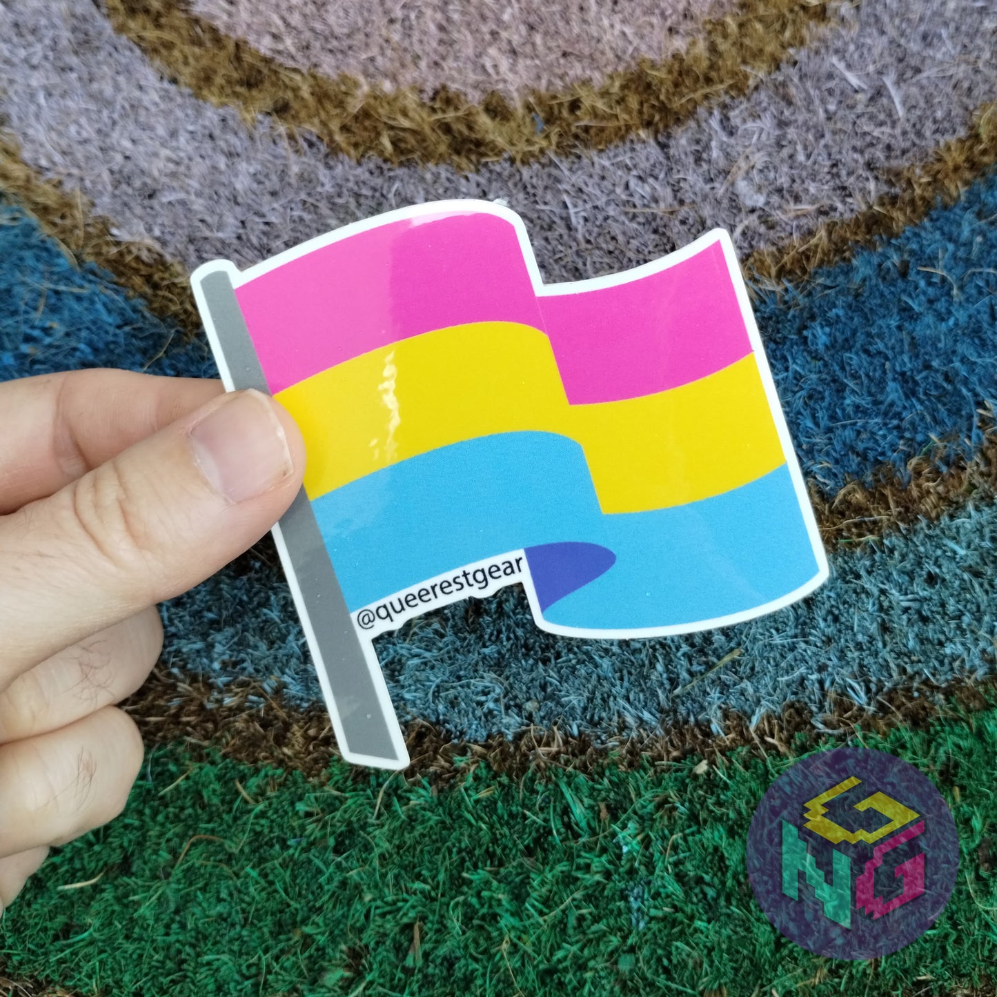 pansexual flag sticker held in front of rainbow welcome mat