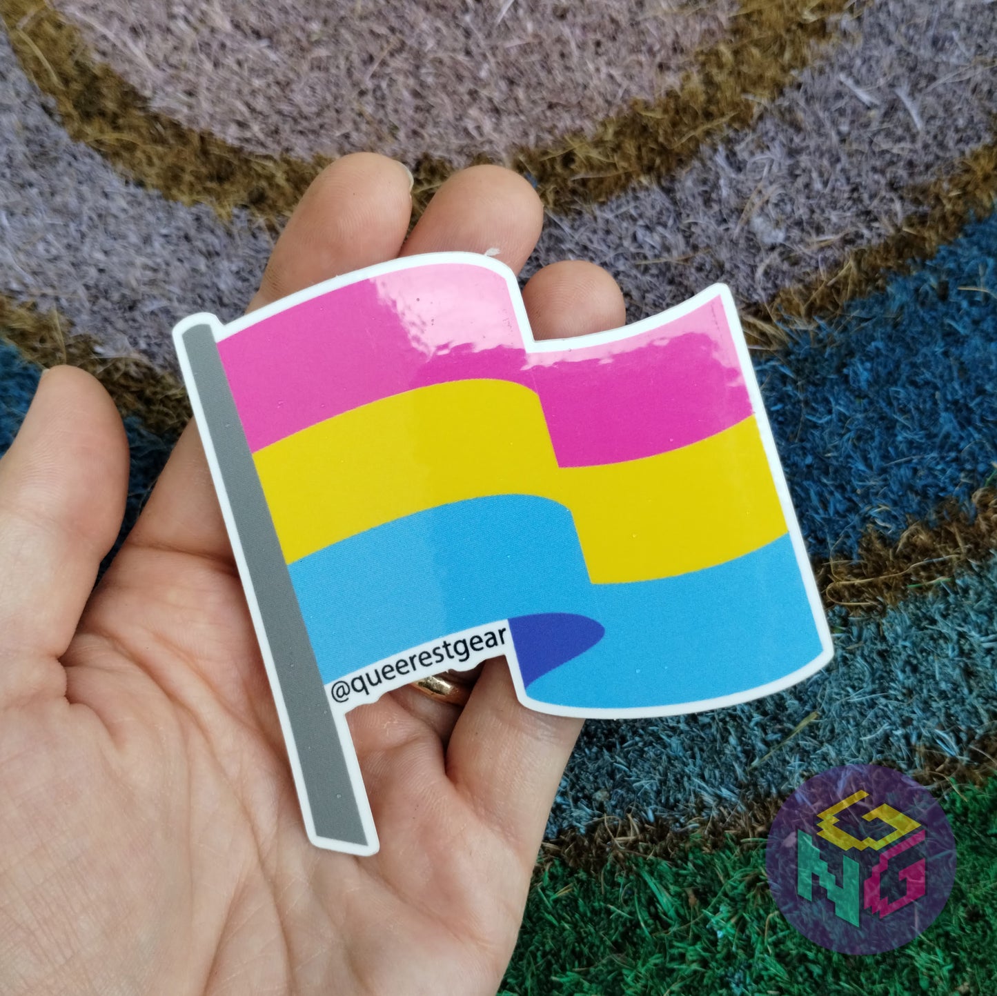 pansexual flag sticker held in hand against rainbow welcome mat