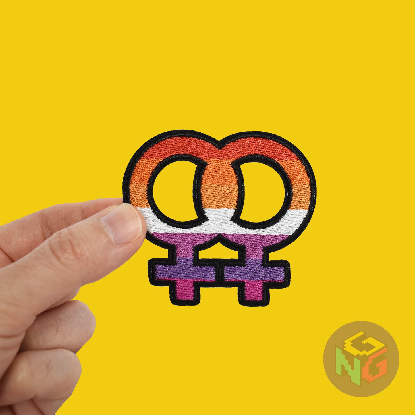lesbian iron on patch being held in a hand in front of a yellow background