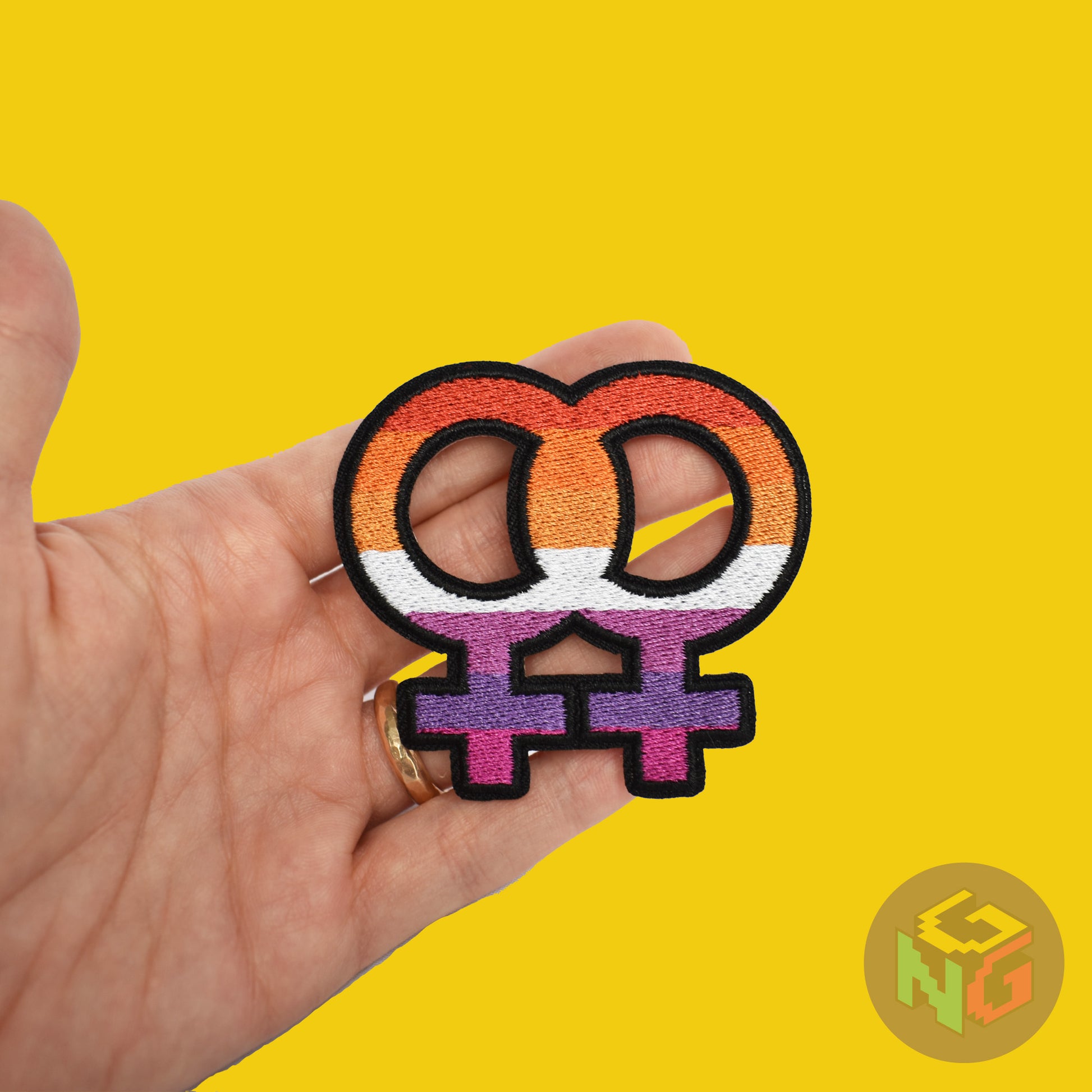 lesbian iron on patch held in hand against yellow background