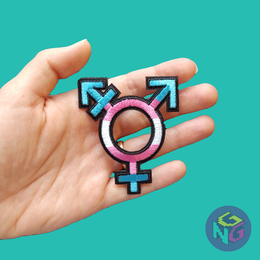 hand holding the transgender embroidered iron on patch in front of mint green background